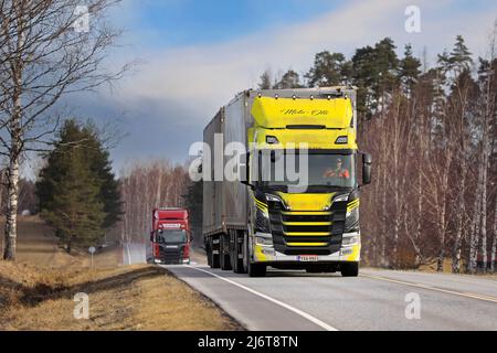 Scania truck and woodchip transport trailer of Moto-Olli Oy and red Scania Huhtala on highway 52 on a spring morning. Salo, Finland. April 18, 2022. Stock Photo