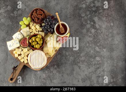 Top view of tasty cheese board with grapes, honey, nuts, olives, and cheese varieties Stock Photo