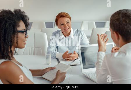 Portrait of businesswoman listening to her employees sitting in front of her Stock Photo