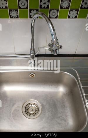 Closeup of the metal sinks with the chrome tap after washing on the modern counter, inside the kitchen of the urban house,  front view for the copy sp Stock Photo