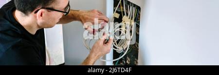 Technician cutting cable to install telecommunication box Stock Photo