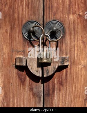 Close up view of old brass door ring handles with padlock on wooden door Stock Photo