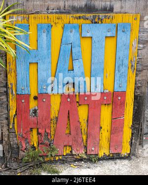 Indonesian cautious sign of blue and red wood cutout letters on yellow painted wood plank. Hati Hati meaning cautious, to be careful. Stock Photo