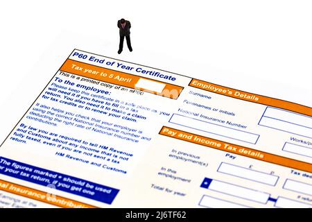 Miniature scale model businessman with a P60 End of year Certificate issued by HMRC in the United Kingdom.  Blank tax form Stock Photo