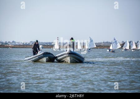 two people on a rubber dinghy are talking to each other on the Gilao River. many small sailing boats can be seen in the background Stock Photo