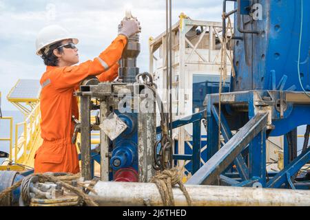 Offshore oil rig worker prepare tool and equipment for perforation oil and gas well at wellhead remote platform. Stock Photo