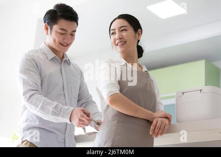 In the family kitchen, husband helped his wife put on the apron, and she looked back in relief - stock photo Stock Photo