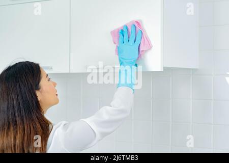 asian woman wearing rubber protective blue gloves standing cleaning with products and equipment kitchen cleaner. Stock Photo