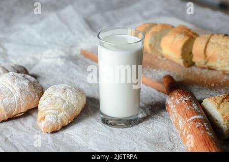 Milk is poured into a glass, bread, croissants Stock Photo