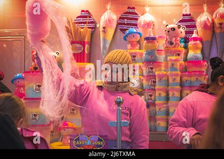 London, UK - December 2, 2021 - A female stuff spinning candy floss at Christmas Hyde Park Winter Wonderland Stock Photo