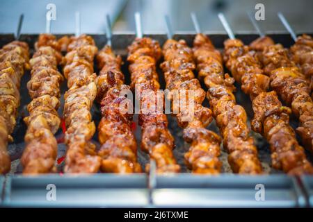 Chicken kebabs cooking on a charcoal grill at Christmas market Hyde Park Winter Wonderland in London Stock Photo