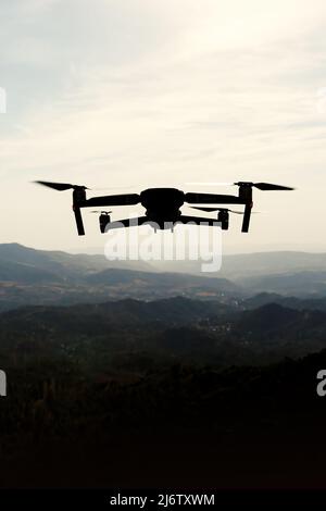 Folding small drone is flying over the mountains. Stock Photo