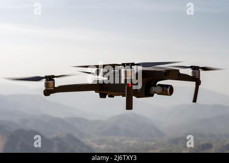 Folding small drone is flying over the mountains. Stock Photo