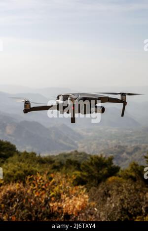 Folding small drone is flying over the mountains. Stock Photo