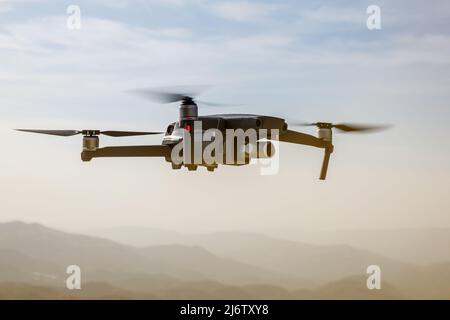 Folding small drone is flying over the mountains. Stock Photo