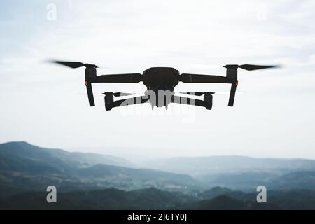 Folding small drone is flying over the mountains. Stock Photo