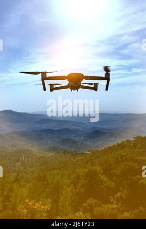 Folding small drone is flying over the mountains. Stock Photo