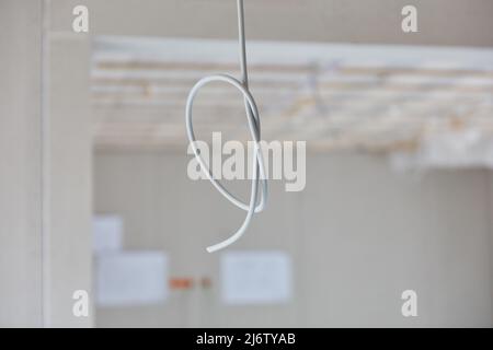 Cable with knots hangs from the ceiling in the interior of a house in a new building Stock Photo