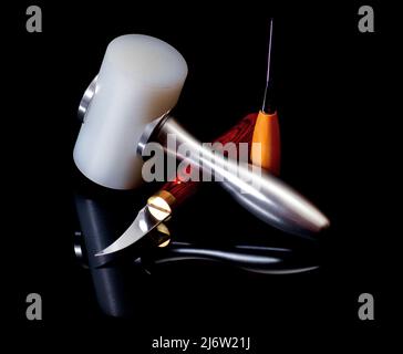 Arrangement of Leather Crafting Tools with Special Hammer, Utility Knife and Piercing Instrument closeup on Black Mirror background Stock Photo