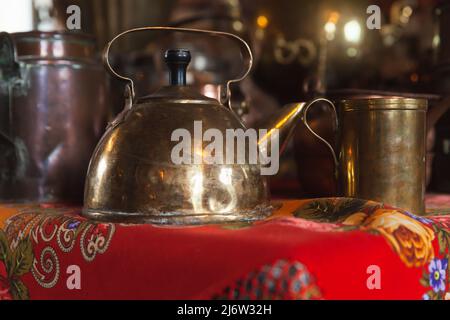 Vintage copper kettle stands on a table near mug, close up photo with selective soft focus Stock Photo