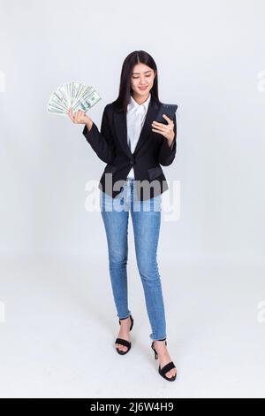 business asian woman wearing office clothing successful hold smart phone mobile and US dollars money in hand feeling happy and smile, bankruptcy econo Stock Photo