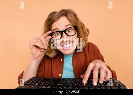 Portrait of handsome trendy cheery red-haired guy playing web game isolated over beige pastel color background Stock Photo