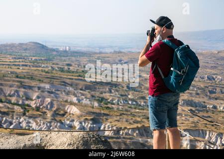Man tourist photographing fairy chimney rock formations and rock pillars of “love Valley” near Goreme, Cappadocia, Nevsehir, Turkey Stock Photo