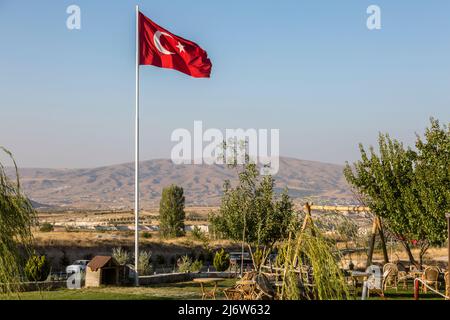 Turkish flag near the horizon in Göreme, Cappadoci. Tourist town with houses in Cappadocia. Stock Photo