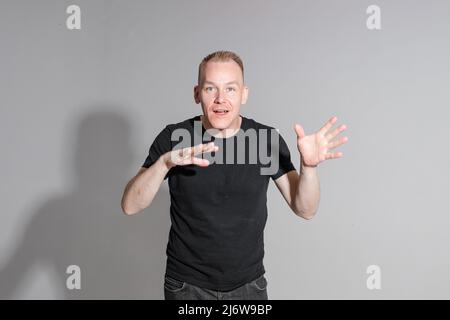 Lively Caucasian man in black shirt posing in grey background Stock Photo