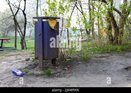 Full trash can and bottle on the ground Stock Photo