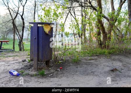 Full trash can and bottle on the ground Stock Photo