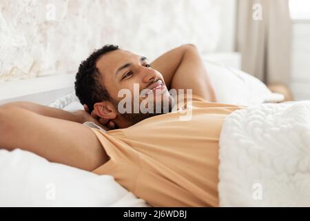 Happy Middle Eastern Man Relaxing Lying Resting In Cozy Bedroom Stock Photo