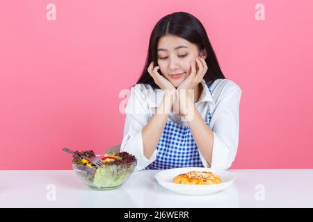 happy young asian woman choose to eat fresh orange apple fruits with copy space pink background, health care eat vegetables and useful foods lifestyle Stock Photo