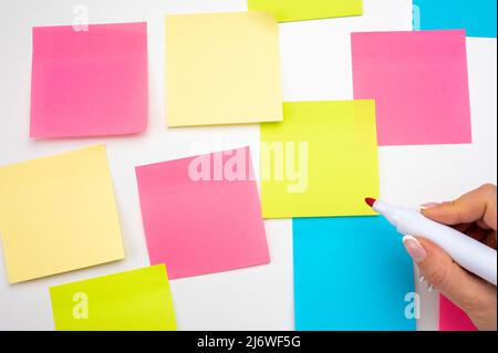 Blank Sticker notes on white background. hand with red marker ready to write. Mockup sticky Note Paper. empty sheets for notes on white bulletin board Stock Photo