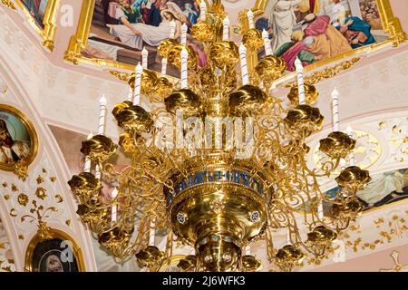 Large gilded chandelier in the temple of God on the background of icons and murals Stock Photo