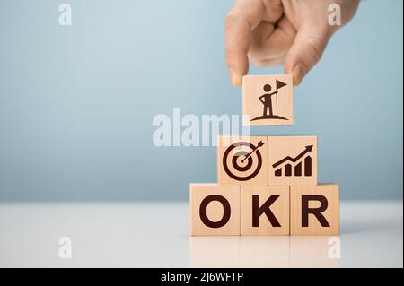 OKR Objectives, Key and Results wooden cube blocks on blue background. Business target and drive business and performance. Business and OKR - objectiv Stock Photo