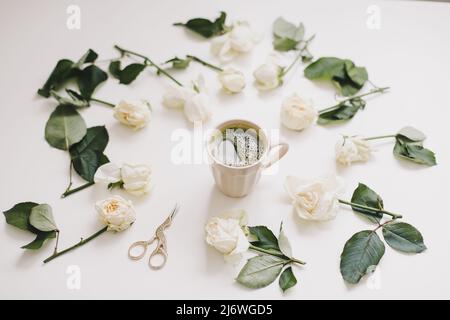 Beautiful composition with cup of matcha tea and flowers on white background. Flatlay, top view, copy space. Stock Photo