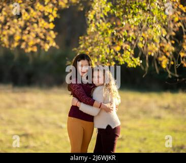 Portrait of two charming kind cheerful girls wearing casual hugging good mood . Stock Photo