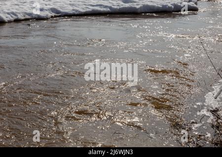 Sunlight reflecting in the water. Spring melting snow. River water ripples shining with sun light. Stock Photo
