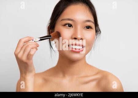 Portrait of beautiful Asian woman with makeup brush Stock Photo
