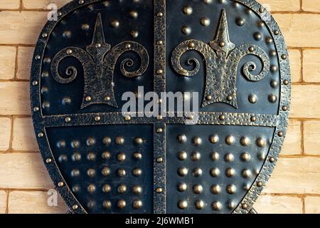 The interior design. A metal shield hangs on the wall as a decoration. Iron shield close up Stock Photo