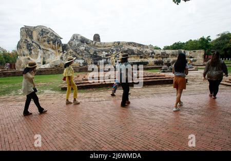 Ayutthaya, Thailand - 4 May 2022, Tourists visit a reclining Buddha at the Wat Lokayasutharam temple in Ayutthaya, north of Bangkok. Stock Photo