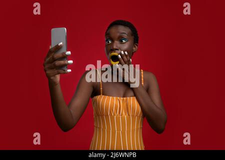 Emotional black lady holding modern cell phone Stock Photo