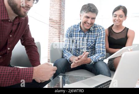 Portrait of smiling executives sitting with laptop in office Stock Photo