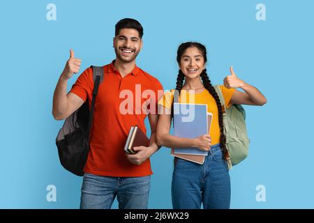 Portrait Of Cheerful Young Arab Students Couple Showing Thumbs Up At Camera Stock Photo