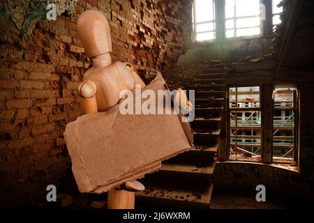 wooden puppet with a poster against the background of a destroyed building. High quality photo Stock Photo
