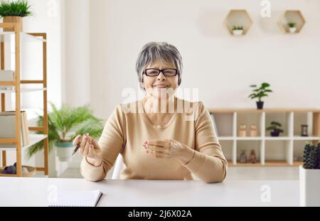 Portrait of happy senior woman during conference call, webinar or online work meeting Stock Photo
