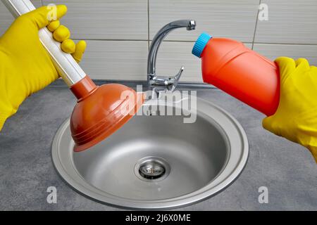 Hands in yellow rubber gloves hold a plunger and pipe cleaner Stock Photo