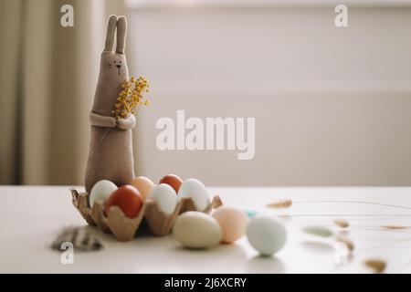 Happy Easter concept. Funny handmade bunny rabbit toy and chicken eggs. Stock Photo