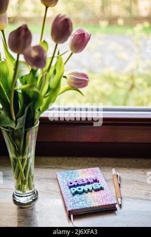 Big dream word on pop color rainbow unicorn shiny notepad and tulips on wooden table. Motivation quote, inspiration, positive affirmation Stock Photo